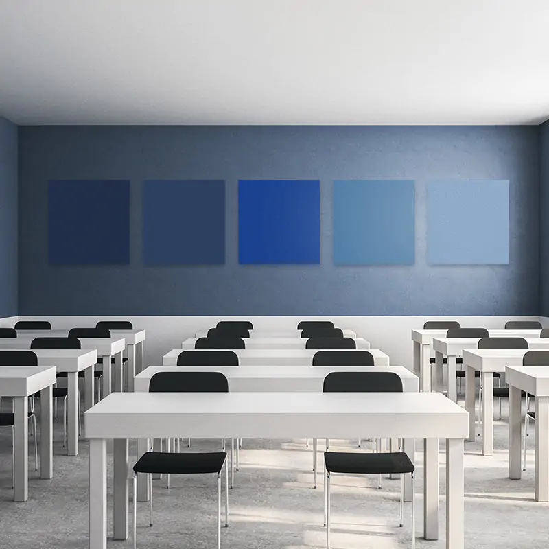 Empty classroom with white tables and black chairs against a blue wall with gradient panels.